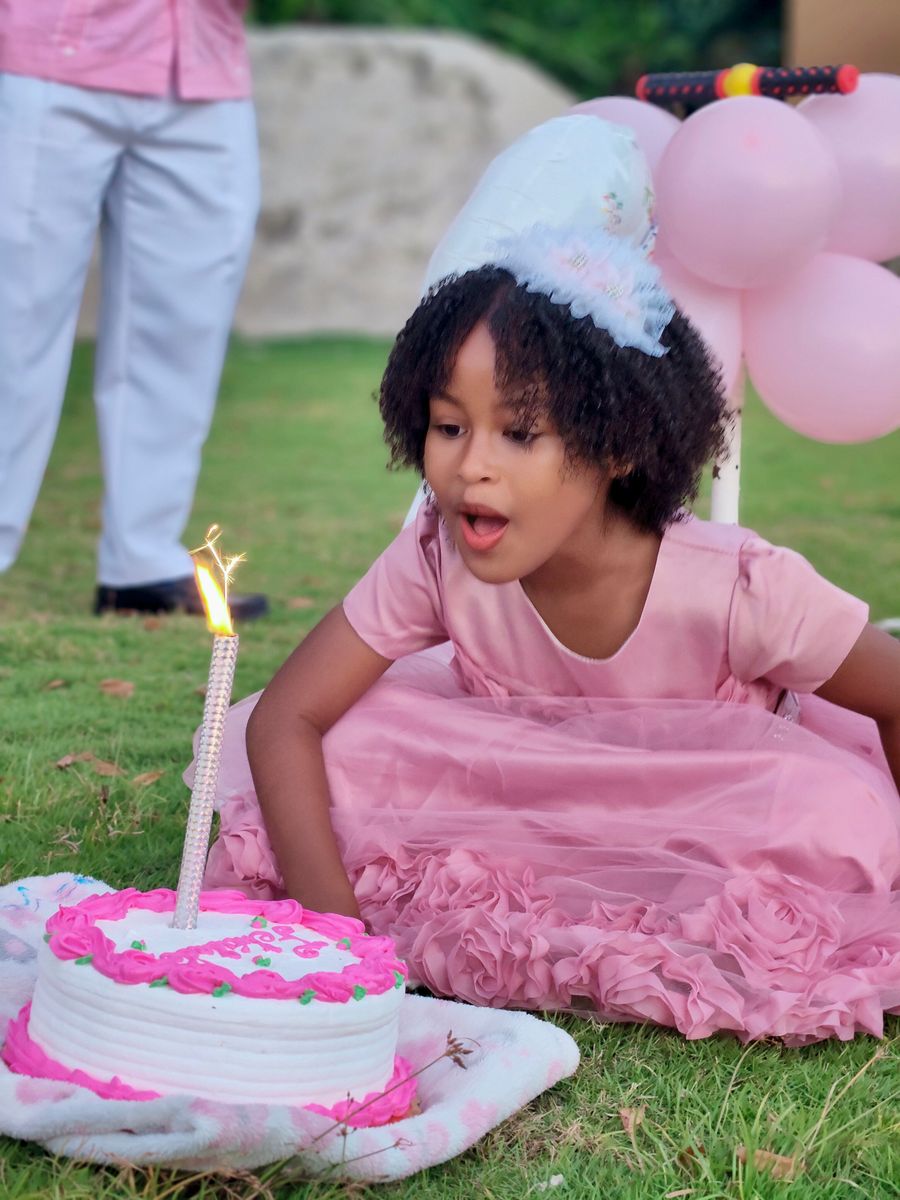 Niña festejando su cumpleaños con pastel y globos