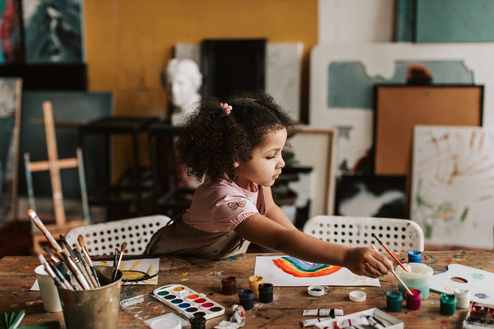 Niña pintando con pinceles en un taller de arte